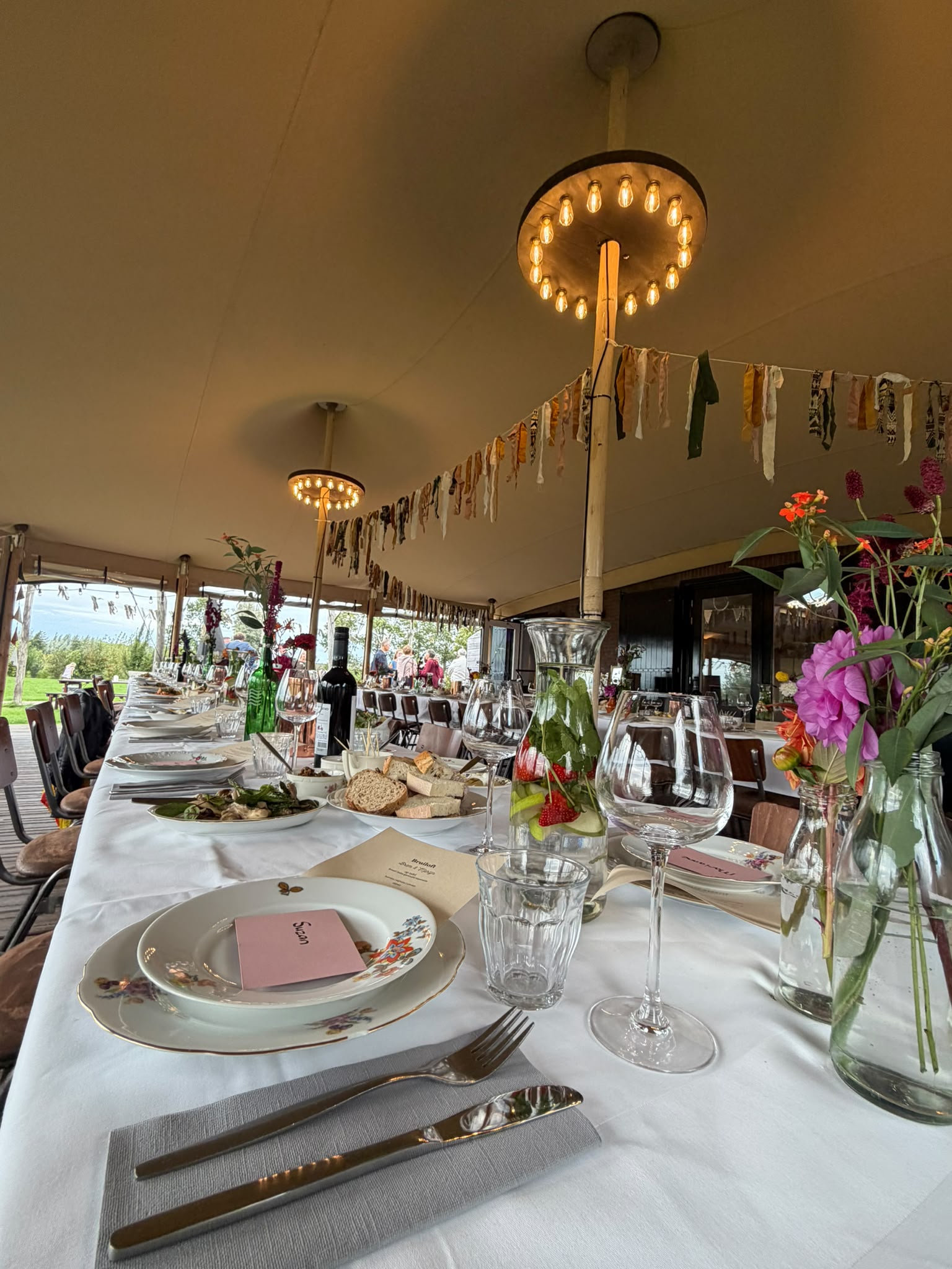 Gedekte lange tafel in een tent met lichtjes