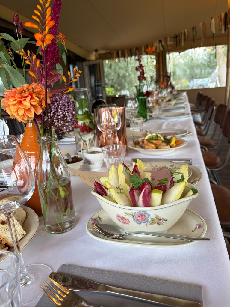 Lange tafel gedekt met vintage servies en bloemen
