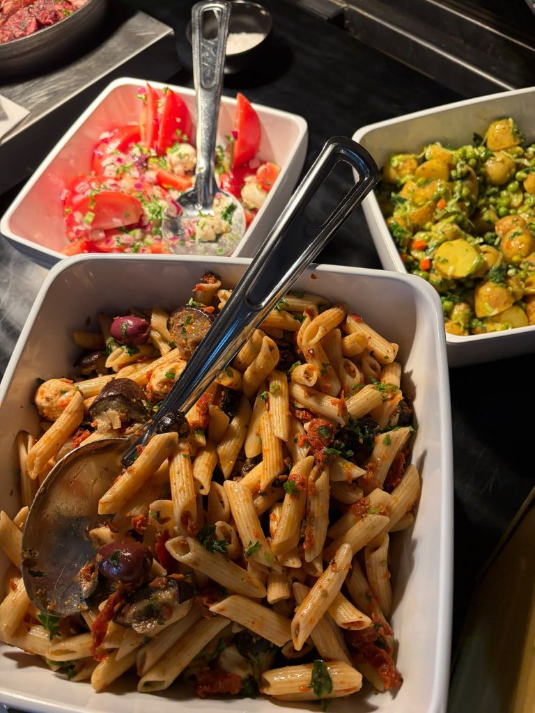 Pastasalade, tomatensalade en aardappelsalade op het buffet